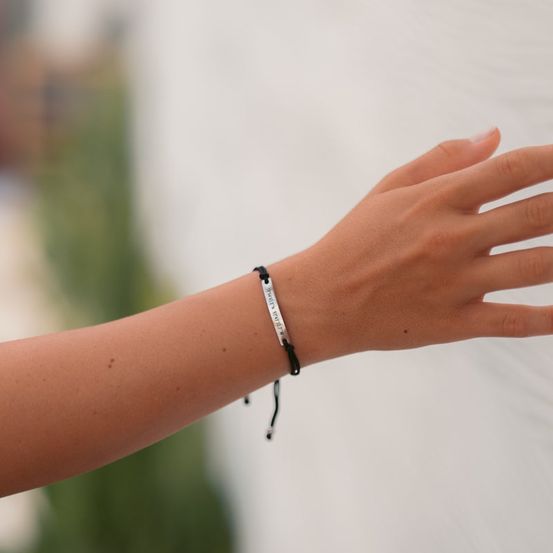 A girl wearing a black thread bracelet with silver bar